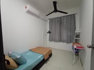 een ziekenhuiskamer met een bed en een plafondventilator bij Kyra's Homestay Melaka in Merlimau