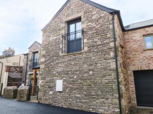 an old brick building with windows and a gate at Macaw Cottages, No 4 in Kirkby Stephen