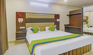 Treebo Trend Kingsbury Fiesta Vellore في فيلوري: غرفة نوم بسرير ابيض كبير مع مخدات خضراء