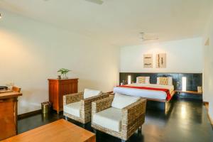 a hotel room with a bed and two chairs at Rainforest Resort in Athirappilly