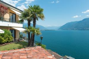 zwei Palmen neben einem Gebäude neben dem Wasser in der Unterkunft Boutique Hotel La Rocca in Ronco sopra Ascona