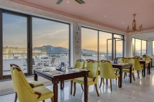 a restaurant with yellow chairs and tables and windows at SHAHPURA DEV PANACHE in Udaipur