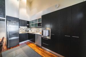 una cocina con armarios negros y electrodomésticos de acero inoxidable en Vietti Suites, en Tahkovuori
