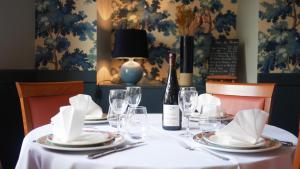 a table with a bottle of wine and glasses at Logis Saint Louis in La Suze-sur-Sarthe