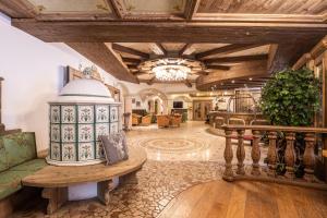 un ampio soggiorno con soffitto in legno e tavolo di Hotel Soreghes Gran Chalet a Campitello di Fassa