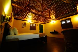 a bedroom with a bed with a straw roof at Malgudi Farms in Bangalore