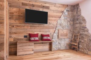 a room with a stone wall with a flat screen tv at Majon Baticher in Canazei