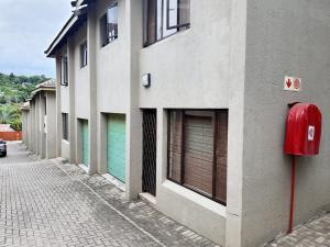 a building with green doors and a red box on a street at NST City Apartments @ 9 Joubert in Nelspruit