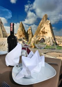 een fles wijn op een tafel met wijnglazen bij Anatelein Boutique Cave Hotel in Uchisar