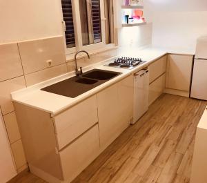 a white kitchen with a sink and a stove at Apartments Velo Lago in Lastovo