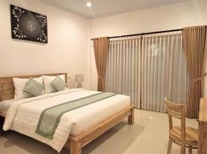a bedroom with a bed and a chair and a window at The Eight Bali - Seminyak in Seminyak