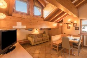 a living room with a couch and a table with a television at Zenith - Casa Azzurra Mansarda in Livigno
