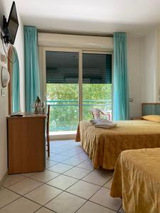 a bedroom with two beds and a large window at Hotel Gadames - Lunch on the Beach in Cervia