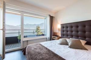 
a hotel room with a large bed and a large window at Seerausch Swiss Quality Hotel in Beckenried
