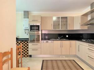 a kitchen with white cabinets and a stove top oven at Charming Calheta Plaza Penthouse in Calheta