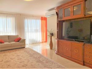 a living room with a large entertainment center with a flat screen tv at Charming Calheta Plaza Penthouse in Calheta