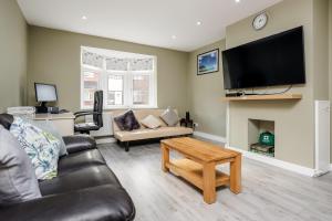 a living room with a couch and a tv at Remaj Serviced Accommodation, sleeps 7 & free parking in Laindon