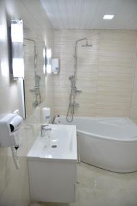 a bathroom with a sink and a tub and a toilet at Hotel Požega in Požega