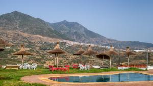 a group of umbrellas and chairs and a swimming pool at Bungalow Double 15 - El Cortijo Chefchaeun Hotel Spa in Chefchaouene