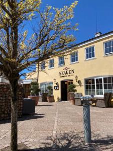 a building with a tree in front of it at Skagen Harbour Hotel in Skagen