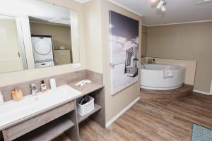 a bathroom with a sink and a tub and a mirror at Hotel Strand No.1 in Sankt Peter-Ording