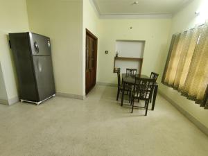 a dining room with a table and chairs and a refrigerator at Kavitha House Homestay in Mysore