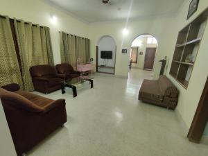 a living room with couches and chairs and a television at Kavitha House Homestay in Mysore