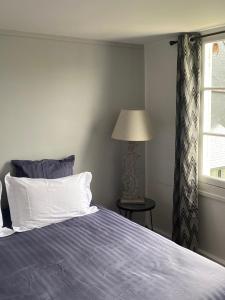 ein Schlafzimmer mit einem Bett, einer Lampe und einem Fenster in der Unterkunft Chambre d’hôtes du Carré des Arts in Honfleur