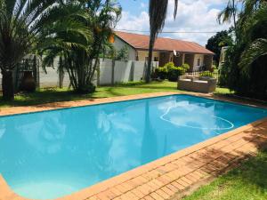 a large blue swimming pool in front of a house at Mopani Guest House in Giyani