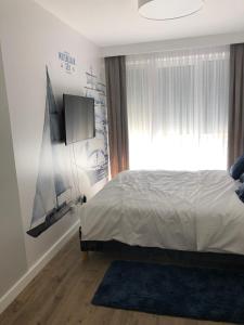 sypialnia z łóżkiem i telewizorem na ścianie w obiekcie Apartamenty Klifowa w Rewalu