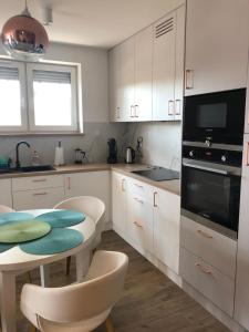 kuchnia z białymi szafkami, stołem i kuchenką mikrofalową w obiekcie Apartamenty Klifowa w Rewalu