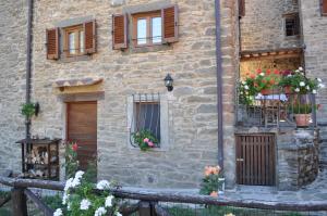 un edificio de piedra con ventanas y flores. en Casa Vacanze Le Antiche Pietre, en Ortignano Raggiolo