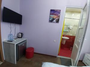 a room with a television and a bathroom with a toilet at Hotel Maria in Batumi