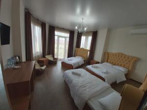 a hotel room with two beds and a desk at Hotel Maria in Batumi
