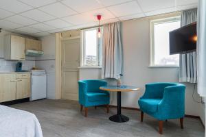 Habitación con 2 sillas azules, mesa y cama en Studio Parkweg, en Bergen aan Zee