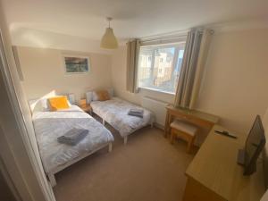 a bedroom with two beds and a desk and a window at Quiet town house by the sea in Broadstairs