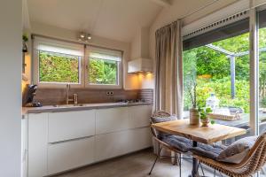 een keuken met een tafel en een tafel en een raam bij Vakantiewoning met privé sauna in Schoorl