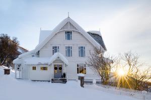 a white house with a white fence in the snow at The Arctic Villa in Tromsø in Tromsø