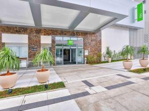 a building with two potted plants in front of it at ibis Styles Goiania Marista in Goiânia