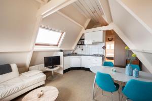 uma sala de estar com uma mesa branca e cadeiras azuis em Appartement Parkweg em Bergen aan Zee