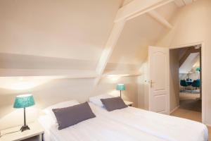 um quarto branco com 2 camas e um espelho em Appartement Parkweg em Bergen aan Zee