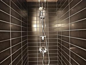 a shower in a bathroom with black tiled walls at Levin Stara 2 in Kittilä