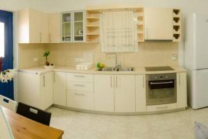 a kitchen with white cabinets and a sink and a refrigerator at Cycladic houses in rural surrounding 3 in Tholária