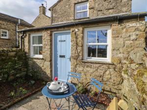 uma casa com uma porta azul e uma mesa e cadeiras em East House em Hawes