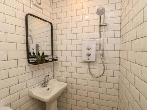 a white tiled bathroom with a sink and a shower at East House in Hawes