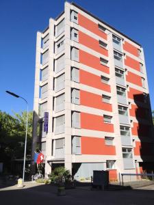 een groot appartementencomplex met oranje en wit bij Residence Tell in Chiasso