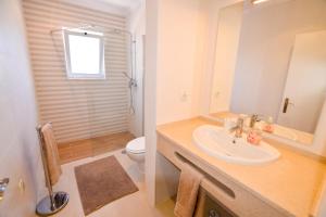 uma casa de banho com um lavatório e um WC em Algarpraia em Carvoeiro