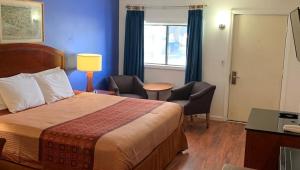 ein Hotelzimmer mit einem Bett, Stühlen und einem Fenster in der Unterkunft Hampton Motor Inn in Hampton
