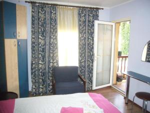 um quarto com uma cama, uma cadeira e uma janela em Complex Vile Daniel em Sinaia