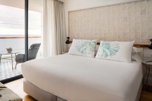 a bedroom with a large white bed and a balcony at Hotel Fariones in Puerto del Carmen